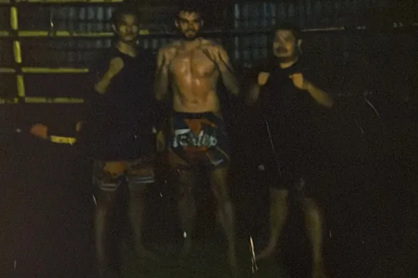 Mateusz Popławski w gardzie z dwoma trenerami na sali Muay Thai w Tajlandii